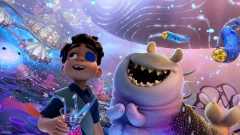 In an image from Disney and Pixar’s Elio, human Elio (left, voiced Yonas Kibreab) and alien Glordon (right, voiced by Remy Edgerly) are standing in the Communiverse, looking around in awe. Ooooo, a liquid supercomputer, is floating to the left of Elio, who is holding a drink with multiple straws and wearing an eyepatch. Both Elio and Glordon are smiling wide, and the scene around them is colorful and bright.