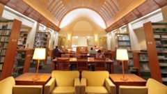 The study floor of a university library with stacks, tables, and chairs