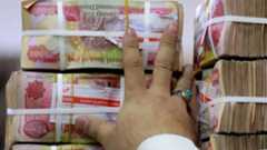 An employee arranges stacks of Iraqi dinars at currency exchange shop in Baghdad on Feb. 14, 2023. (AFP)