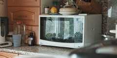 Image of a kitchen countertop with a microwave, kettle, and various kitchen items neatly arranged.
