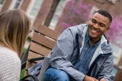 Student sitting on bench chatting with another person