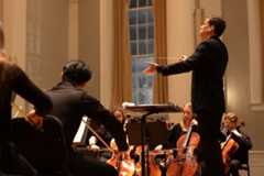 A conductor leads the orchestra in a musical performance