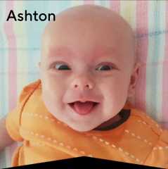 Baby Ashton laying on a blanket poking his tongue out cheekily