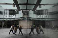 Pedestrians are reflected as they walk outside BBC Broadcasting House in London