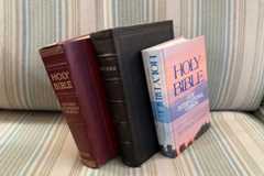 Three bibles sit on a couch.