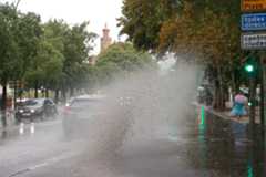 Un coche circula por una calle empapada por la lluvia en Sevilla.