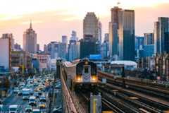 A subway train on the 7 line in Queens, with New York City's Manhattan skyline in the background.