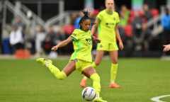 Croix Bethune, in a yellow Washington Spirit jersey, winds up to take a shot