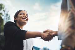 Business people, handshake and meeting in city for partnership, greeting or introduction and welcome outdoors. Happy woman with smile shaking hands for b2b, collaboration or agreement in deal outside