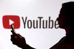 FILE PHOTO: Illustration shows a teenager posing for a photo while holding a smartphone in front of a YouTube logo