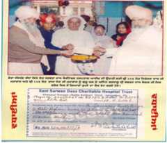 Figure 9: Sant Niranjan Dass receiving money from the Bangar family for The Sant Sarwan Dass Charitable Eye Hospital, Ballan  Inspired by the DSSDB, the Bangar family had been organizing an annual eye camp at Ballan since 