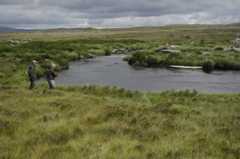 Anglers on river set in wild bogland scenery with mountains in far distance