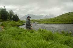 Angler fishing on river with mountains in background