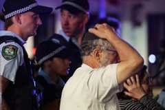 A member of the Jewish community reacts as he walks with police toward the scene of a shooting at Bondi Beach in Sydney Dec. 14.