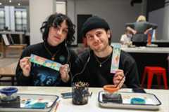 Young couple holding up bookmarks they painted in ArtQuest