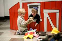 Two young boys playing in a barn puppet theater