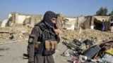 A Taliban security officer stands near a damaged house in Kandahar province on October 16.