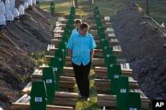 FILE - A Bosnian man walks among graves during a funeral ceremony for the 136 victims at the Potocari memorial complex near Srebrenica, 150 kilometers (94 miles) northeast of Sarajevo, Bosnia and Herzegovina, July 11, 2015.