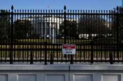 A photo of the outside of the White House and the gate surrounding it. A sign reads "Restricted Area: Do Not Enter."