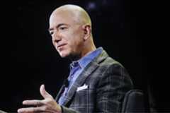 Jeff Bezos pictured from the side while speaking against a black background