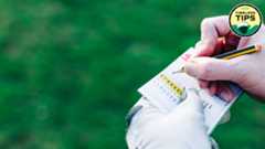 A male golfer writes his score - daytime view