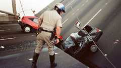 California Highway Patrol officer checks the damage to cars that fell when the upper deck of the Bay Bridge
