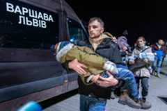A volunteer carries a Ukranian child as civilians fleeing the conflict in Ukraine, arrive on buses in Przemsyl, eastern Poland, from the Medyka pedestrian border crossing.