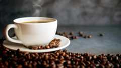 A steaming cup of coffee surrounded by coffee beans