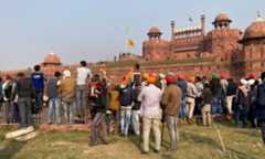 Farmers and others watch after Sikhs hoisted a Sikh religious flag, on a minaret of the historic Red Fort monument in New Delhi on Jan 26. &mdash; AP