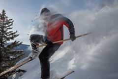 a skier blasting through powder on wooden, horsehide-bottomed skis with a single pole