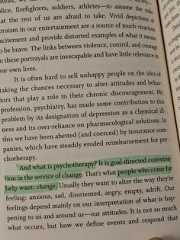 an open book with green highlights on the page and in front of it is a hand holding a piece of paper