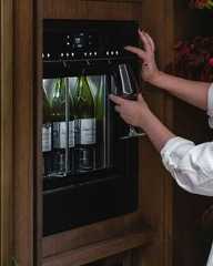a woman is holding a wine glass in front of a cabinet with bottles and glasses