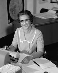 a woman sitting at a desk in front of a typewriter and keyboard, smiling for the camera