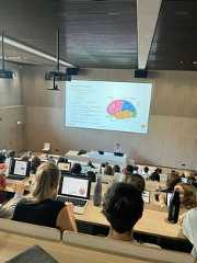 people sitting at desks with laptops in front of them and a projector screen on the wall