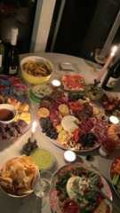 a table filled with plates and bowls of food next to bottles of wine on top of a table