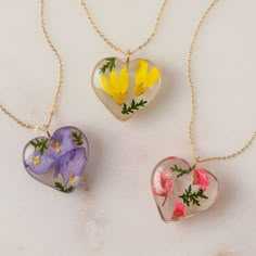 three heart shaped necklaces with flowers painted on them