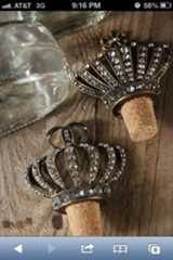 two wine corks with crowns on them sitting next to a bottle opener and glass