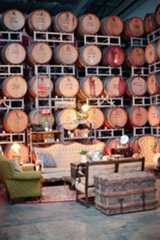 a room filled with lots of wooden barrels on the wall next to chairs and tables