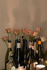 several wine bottles with roses in them on a table next to candles and other items