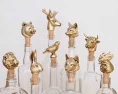 several glass bottles with gold animal heads in them and one has a corked top