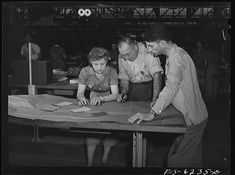 an old black and white photo of three people at a table working on some papers