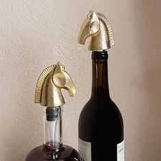 a bottle with a gold horse head on top of it next to a wine bottle