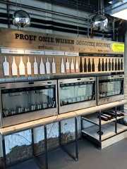 an industrial kitchen with lots of wine bottles on the shelves and lights hanging from the ceiling