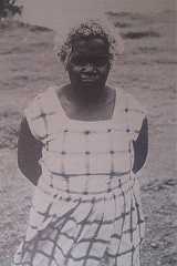 an old black and white photo of a woman standing in front of the ocean with her hands on her hips