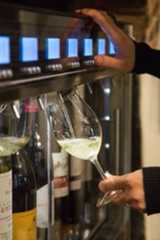 a person is holding a wine glass and reaching for some wine in front of them