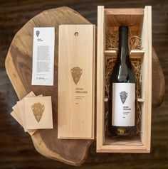 a bottle of wine sitting in a wooden box next to some cards and papers on a table