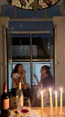 two women sitting at a table with wine and candles