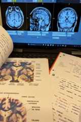 a laptop computer sitting on top of a desk next to an open book and papers