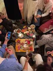 a group of people sitting around a table with food and drinks on top of it