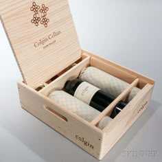 an open wooden box containing two bottles of wine and three napkins in the bottom